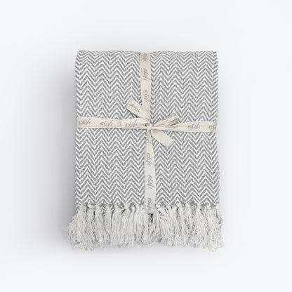 Off white and grey herringbone blanket made from cotton. White chevron throw with tassels. 