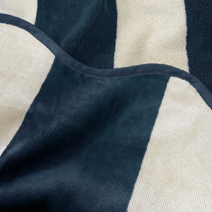 Close up of striped reversible beach towel with terry cloth and velour feel, navy blue colour.