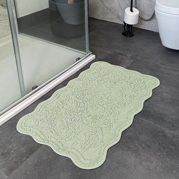 Green scalloped bath mat with a textured floral pattern - made from 100% cotton.