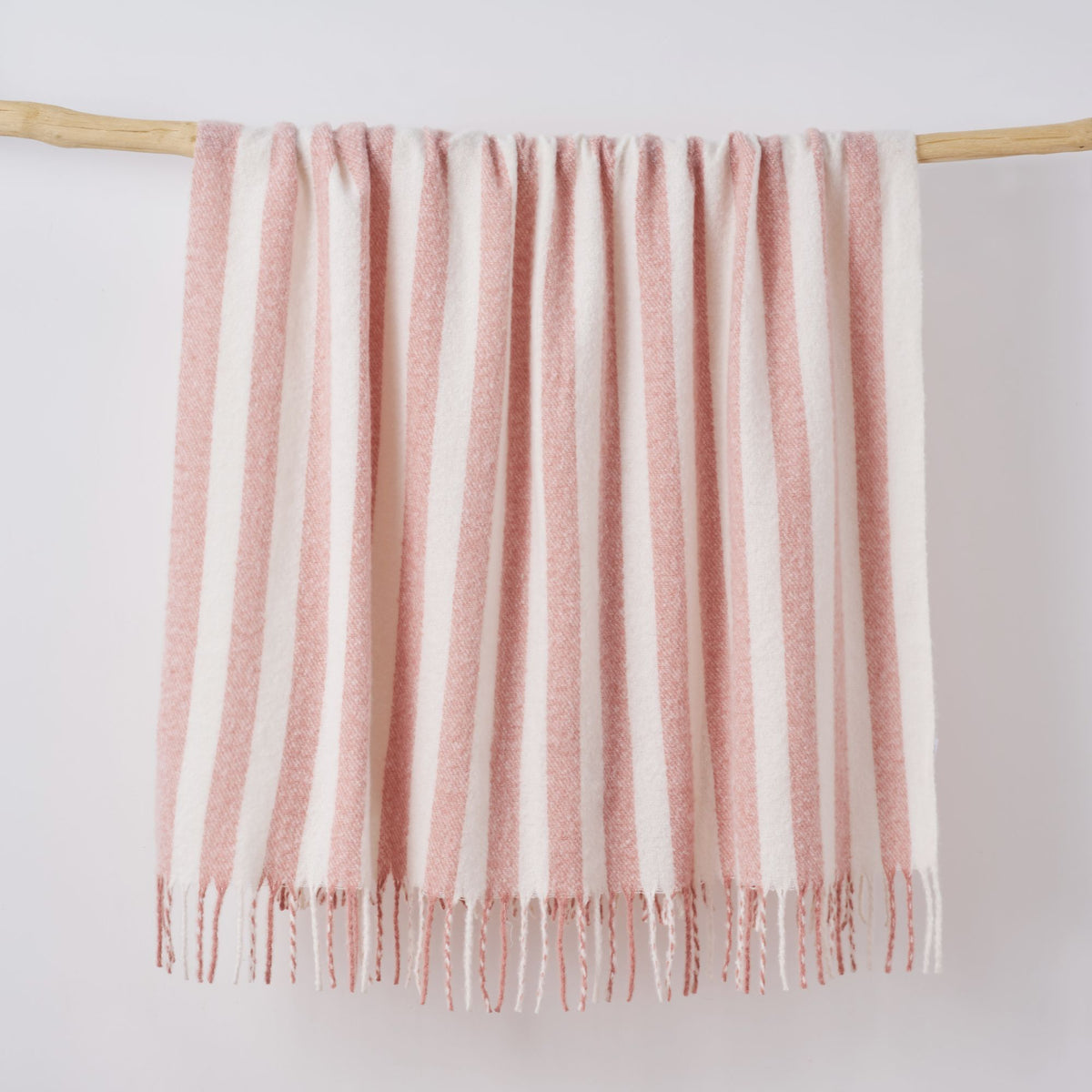 Pink and white throw blanket hanging on a wooden display.