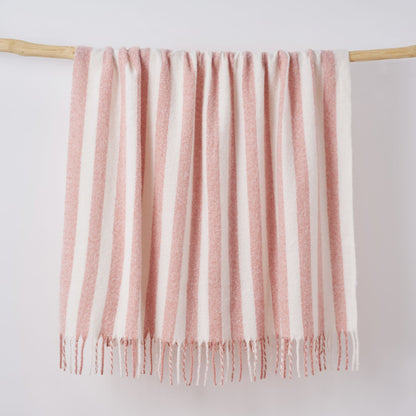 Pink and white throw blanket hanging on a wooden display.