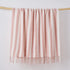 Pink and white throw blanket hanging on a wooden display.