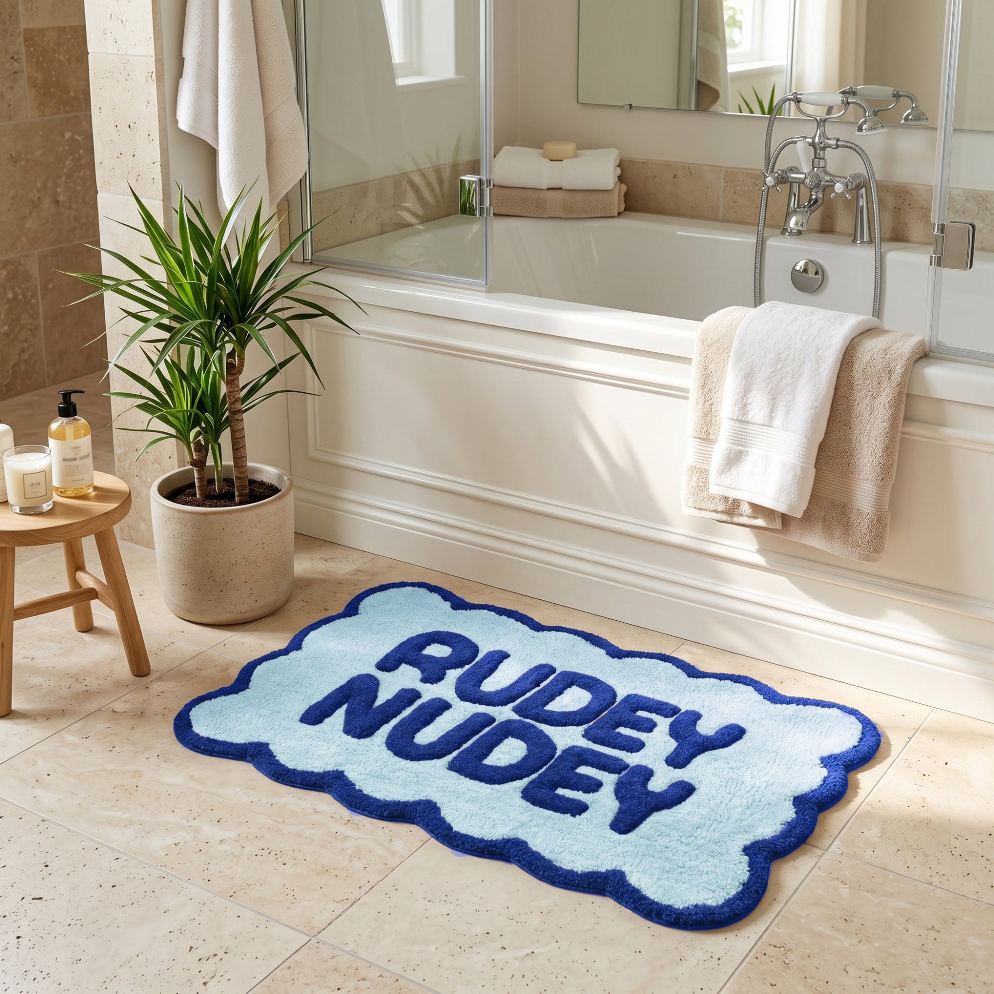 Bright blue statement bath mat with rudey nudey slogan and scalloped edges.