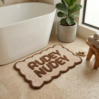 Brown and cream scalloped bath mat with rudey nudey slogan - fun but neutral bathroom styling.