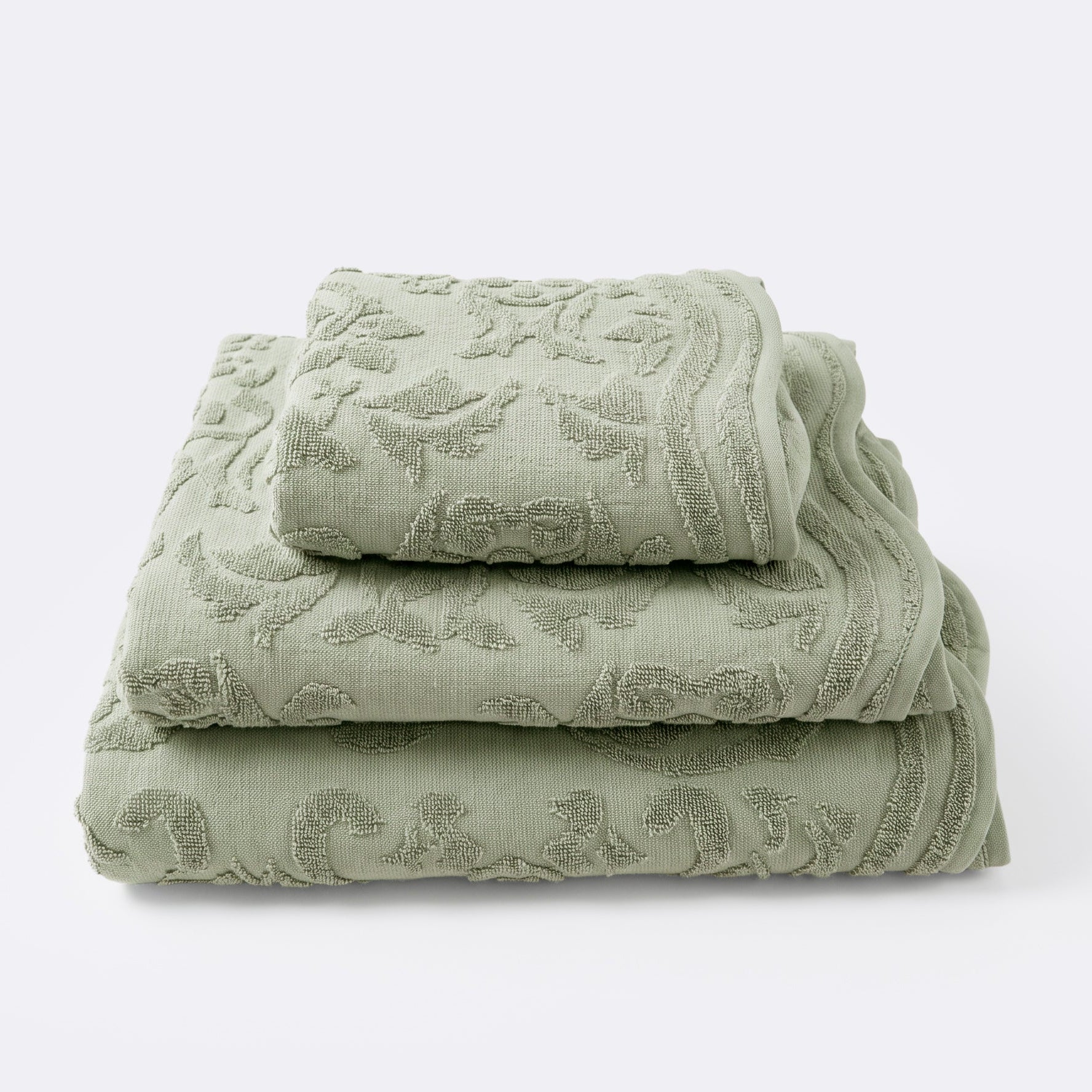 Set of towels for the bathroom with textured floral pattern, hand towel, bath towel and bath sheet in sage green colour.