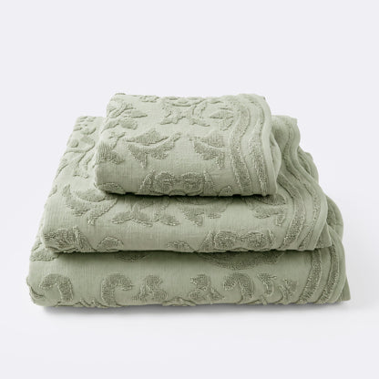 Set of towels for the bathroom with textured floral pattern, hand towel, bath towel and bath sheet in sage green colour.