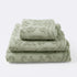 Set of towels for the bathroom with textured floral pattern, hand towel, bath towel and bath sheet in sage green colour.