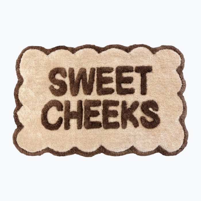 Scalloped bath mat with sweet cheeks slogan in neutral brown and beige colours.
