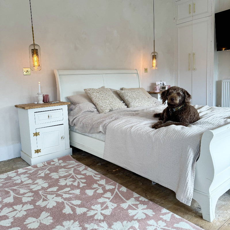Labradoodle laying on a large bedspread on a king size bed.