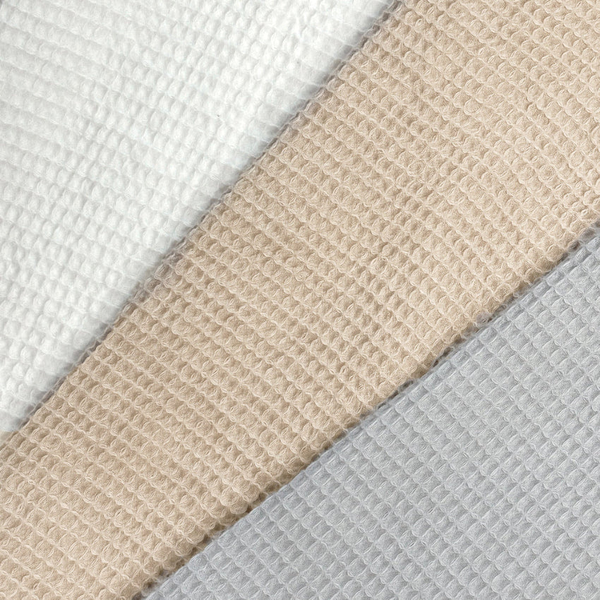 Waffle robe dressing gown close up of the textured material - beige, white and grey.