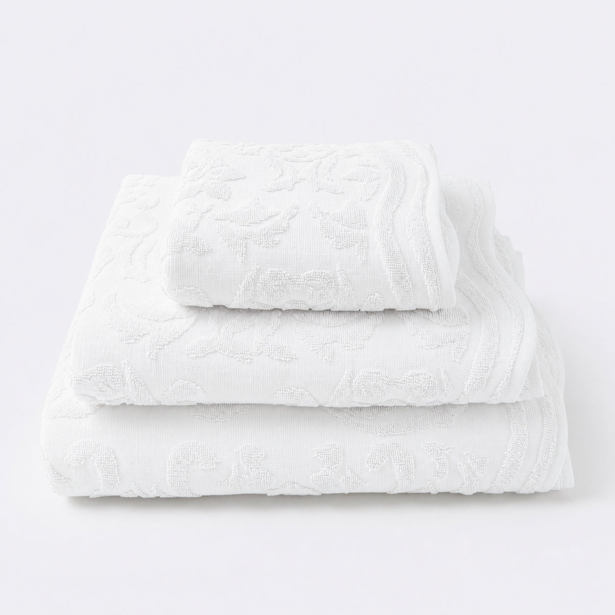 Set of towels for the bathroom with textured floral pattern - hand towel, bath towel and bath sheet in white.